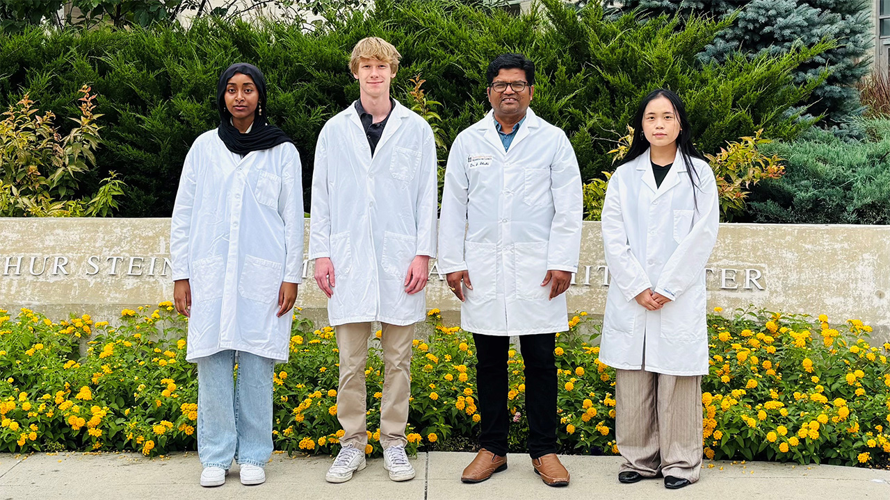 Dr. Shahi and lab members standing in front of flowers