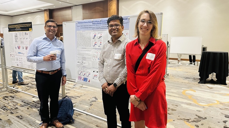 Three people smiling in front of a research poster