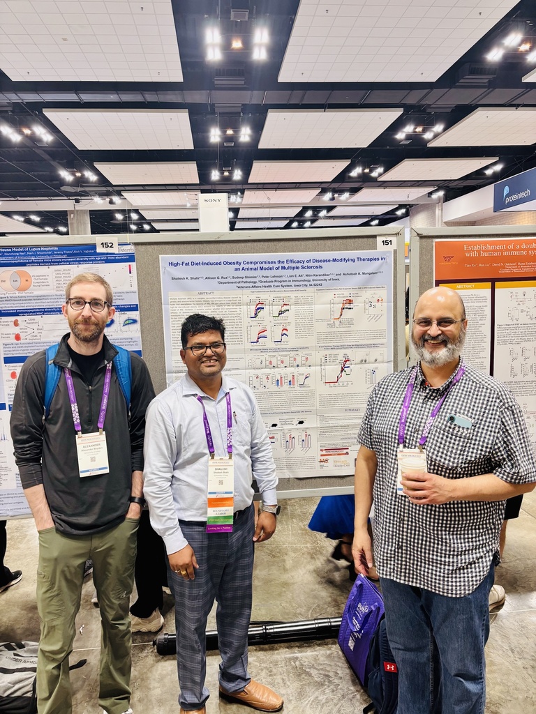Three people smiling in front of a research poster