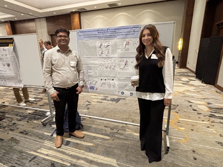 Two people smiling in front of a research poster