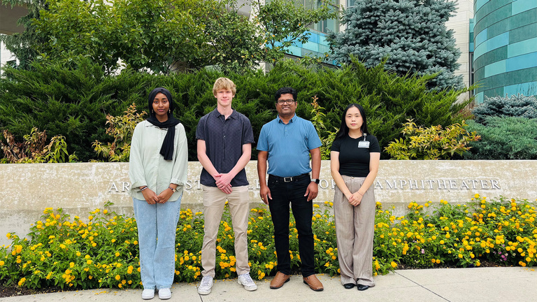Dr. Shahi and lab members standing in front of flowers