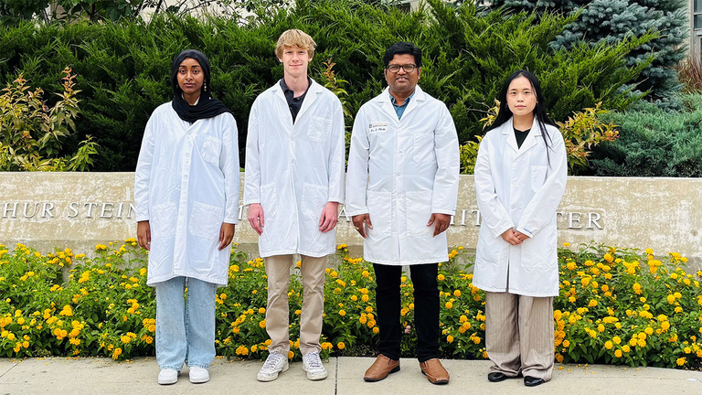 Dr. Shahi and lab members standing in front of flowers