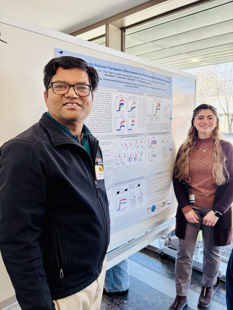 Two people in front of a research post smiling