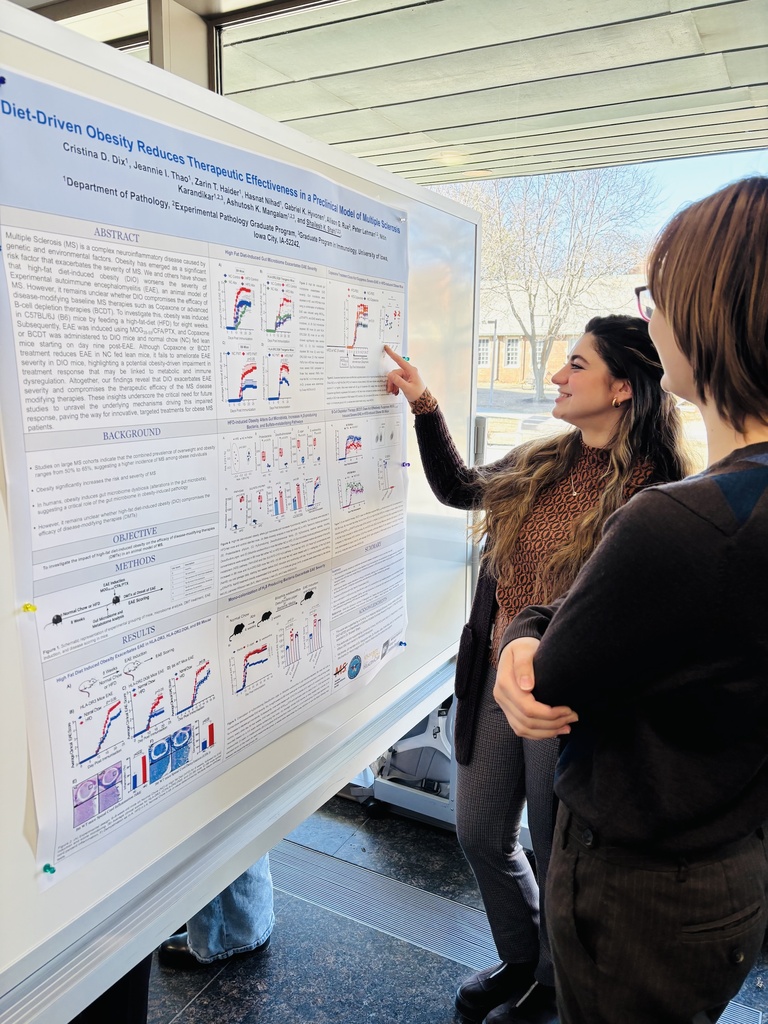 Two people looking at a research poster, one pointing at it