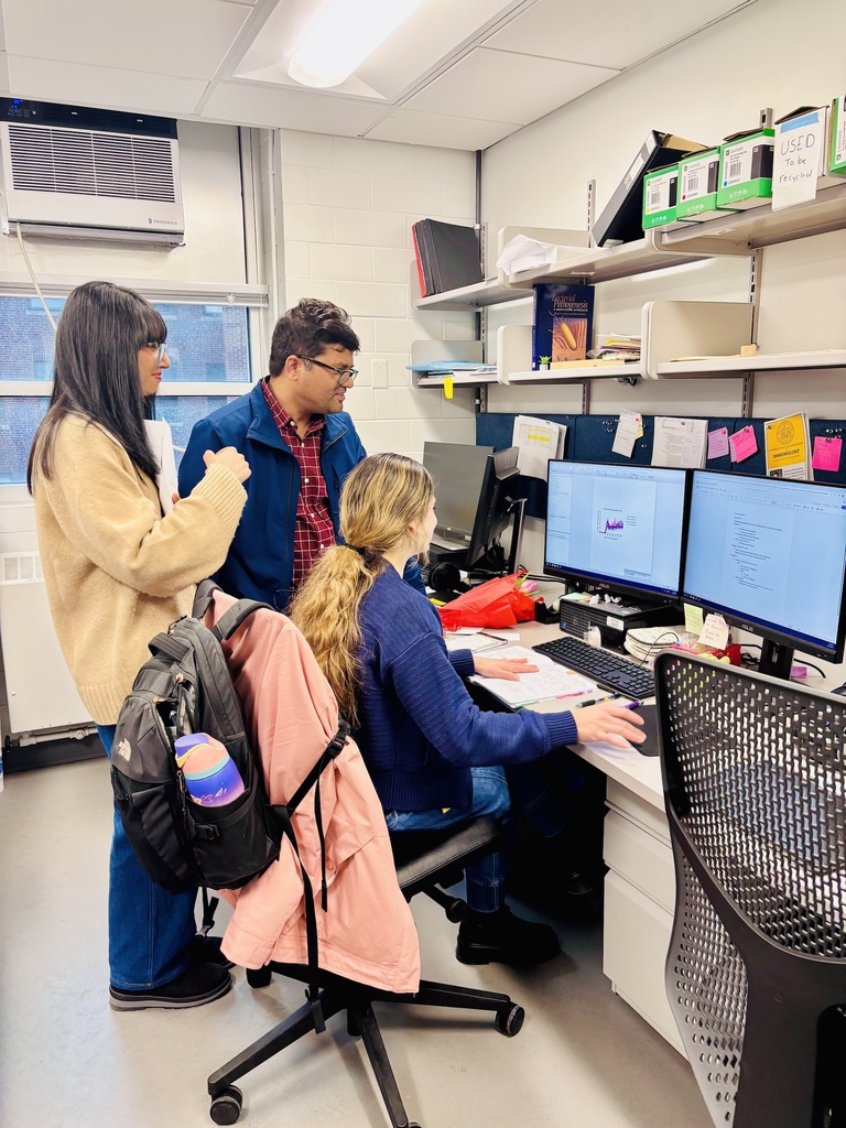 Three people looking at a computer screen in Shahi lab